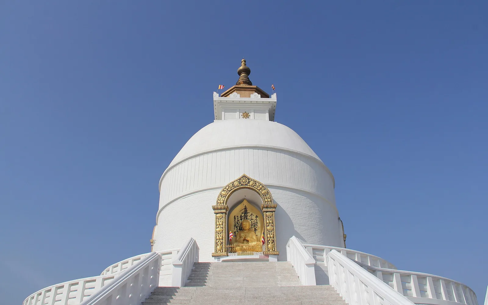 The white dome of the World Peace Pagoda above Pokhara, with a golden Buddha in its niche
