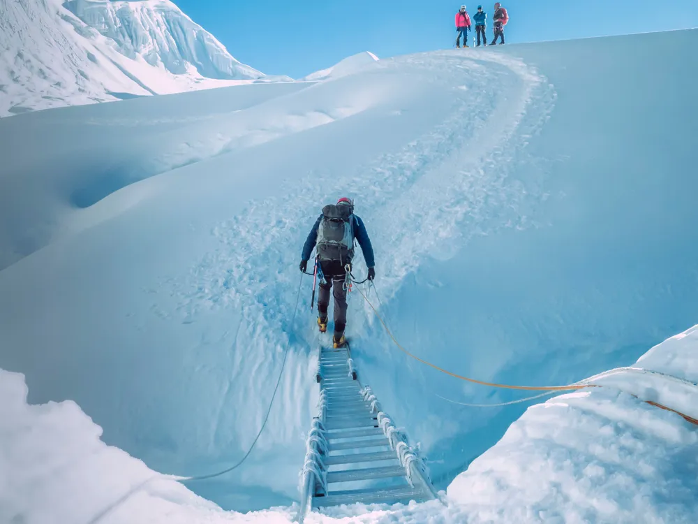 Climbers crossing a snow ridge on fixed ropes
