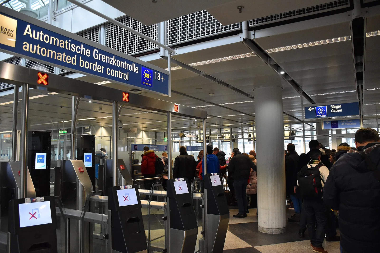 Travellers at airport passport-control booths at a European Schengen border — illustrating 2026 entry-rule changes