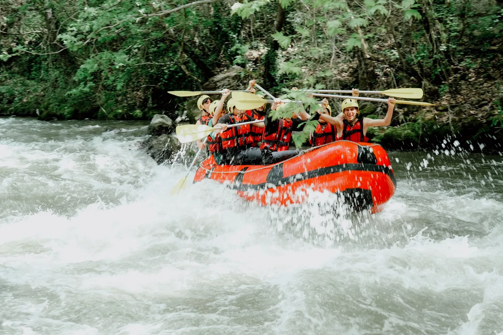 A rafting crew paddling hard through white-water rapids — the kind of adventure activity that standard travel insurance excludes unless you add specialist cover