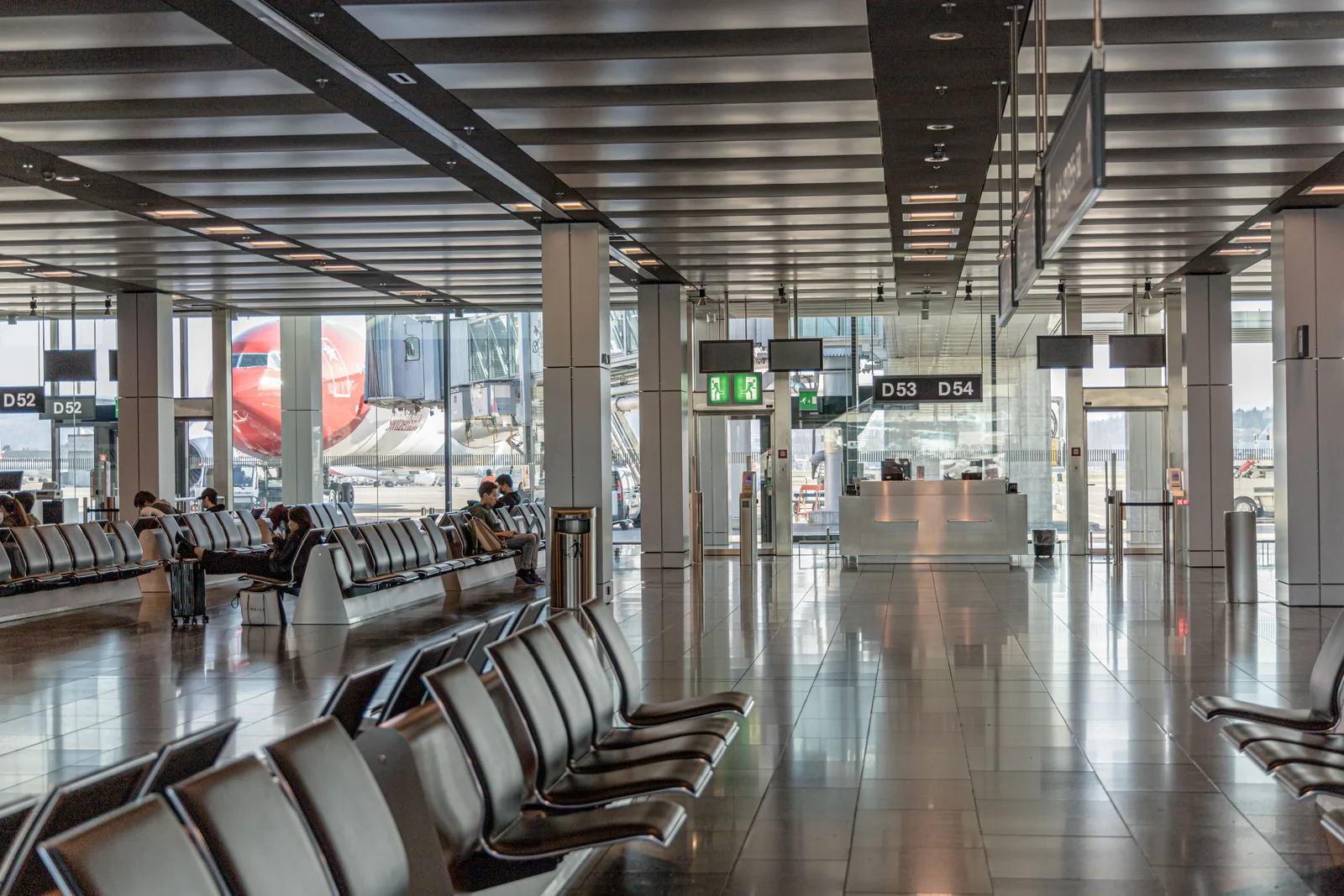 Spacious airport terminal with empty lounge seating and an airplane visible through large glass windows