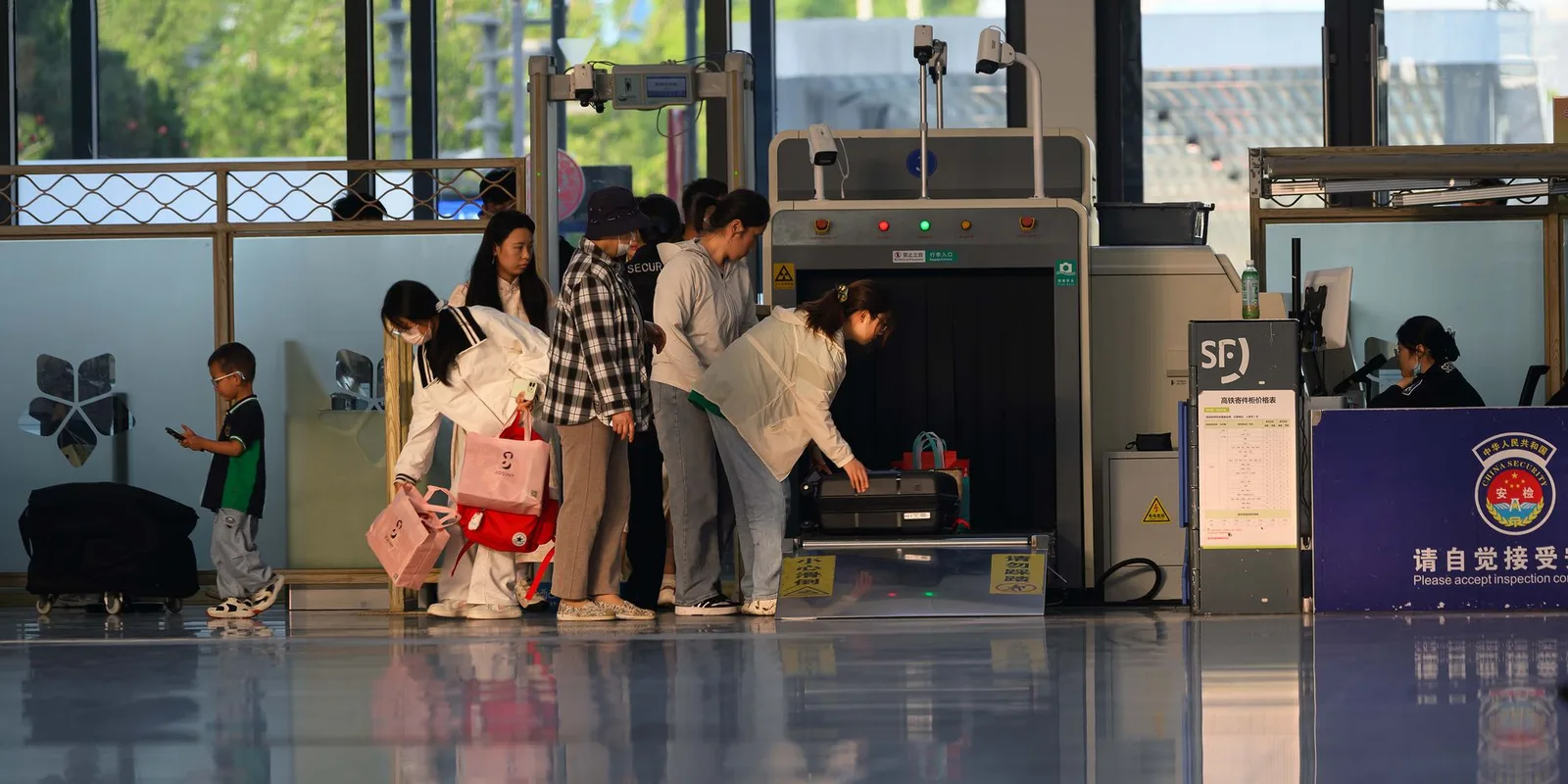 Hand luggage and liquids in a tray going through an airport security scanner at a checkpoint