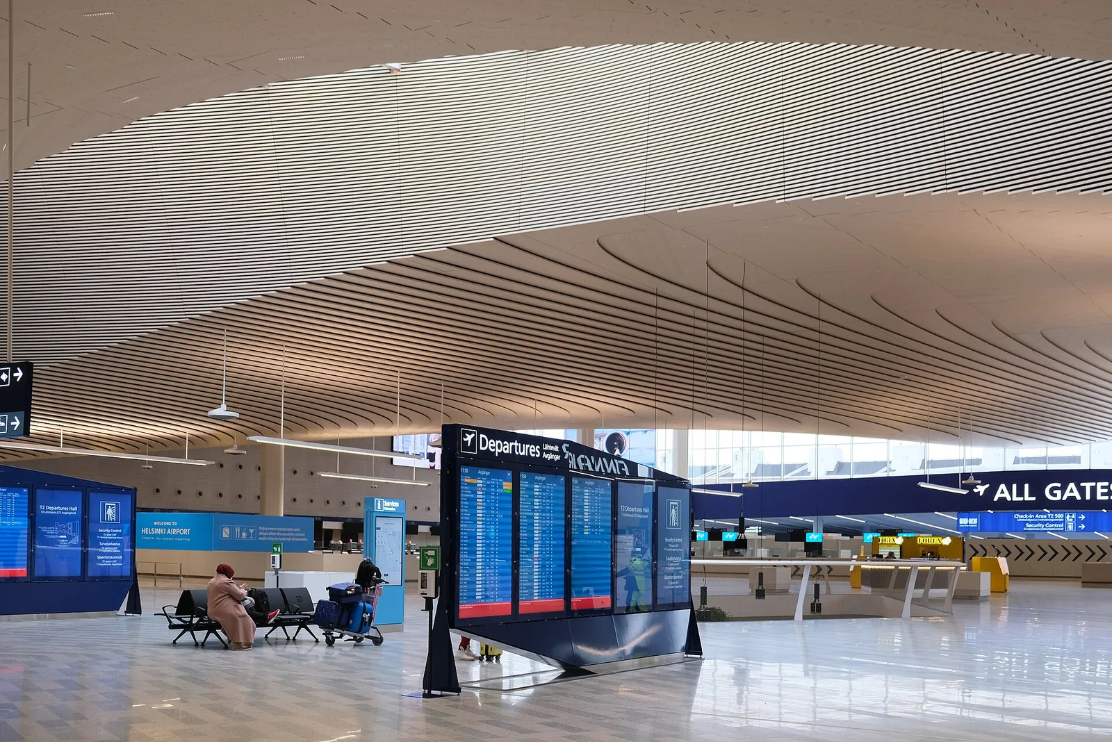 Travellers with luggage in an airport departure hall — weighing annual multi-trip against single-trip travel insurance for 2026