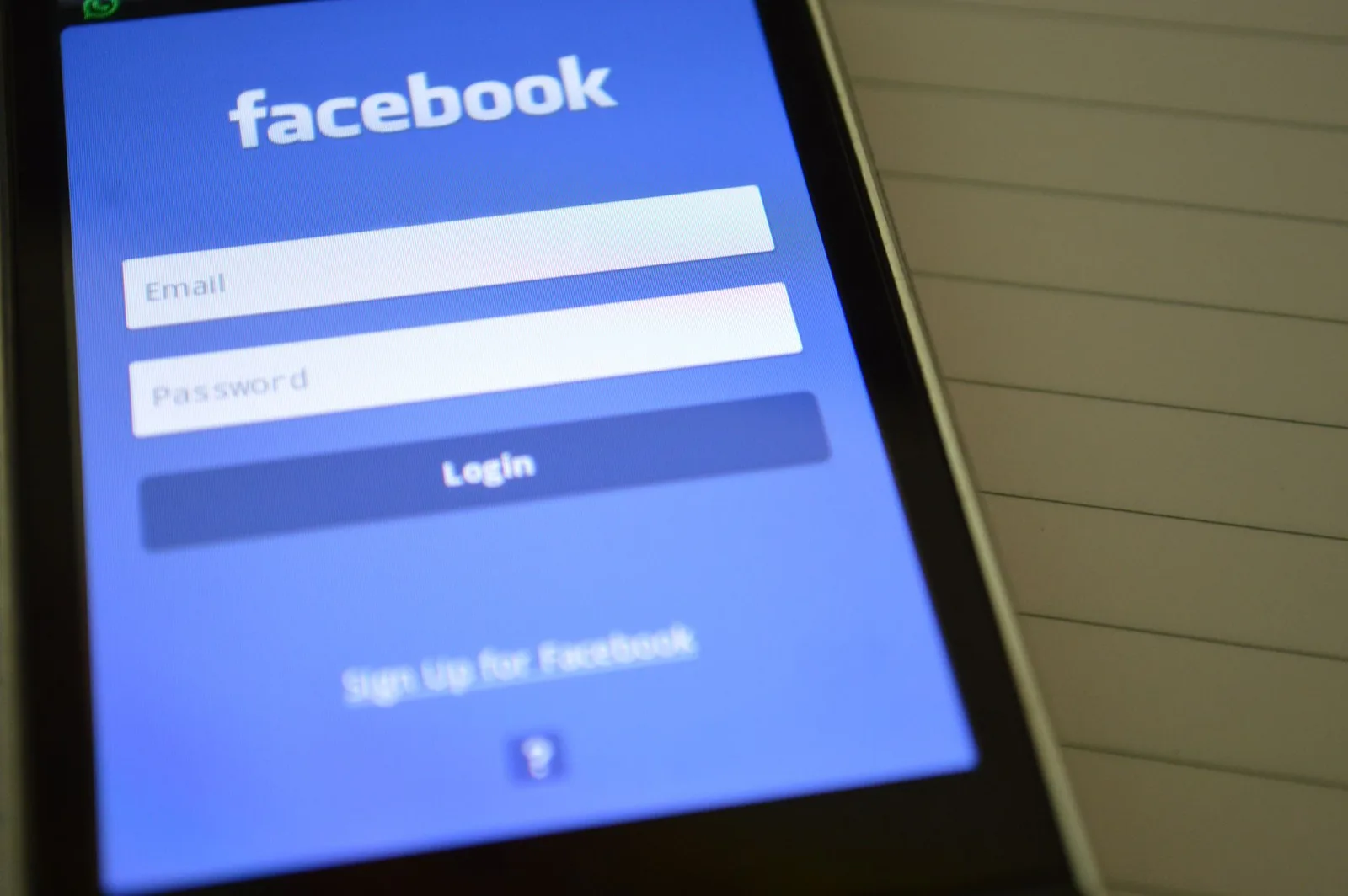 A person entering a two-factor authentication login code on a smartphone while holding a laptop