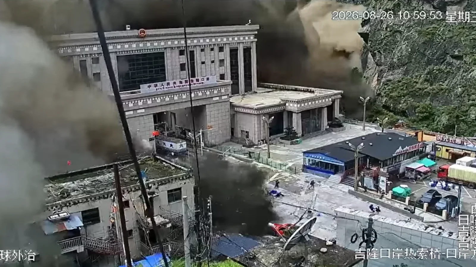 Security-camera footage from the Gyirong Port customs complex on the Nepal-Tibet border at 10:59:53 China time on 26 August 2026 &mdash; 08:44 in Nepal &mdash; as the debris flow reaches the buildings and people run from the forecourt. Public domain, via Wikimedia Commons.