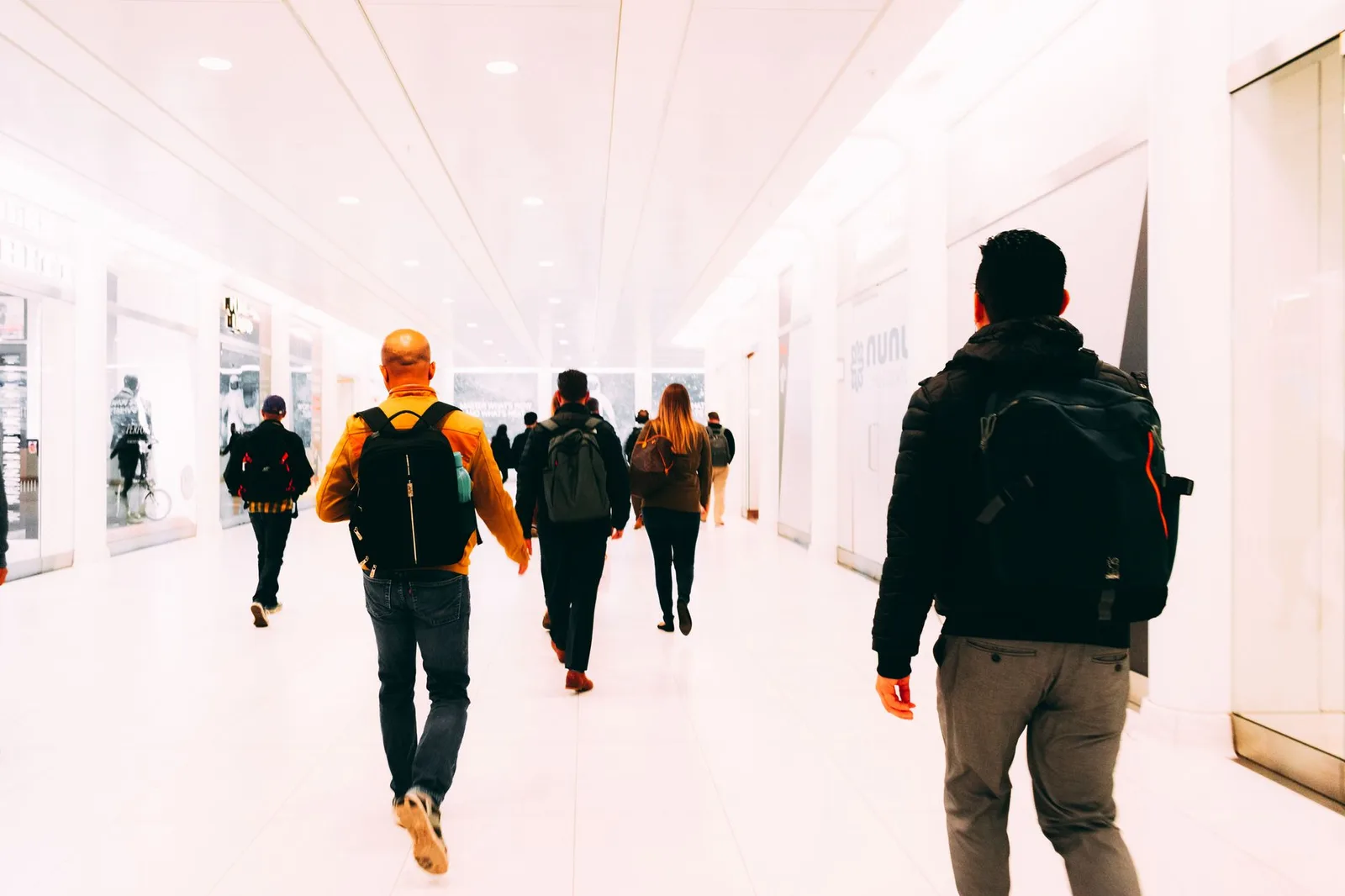 Travellers carrying backpacks walk through a bright modern airport terminal