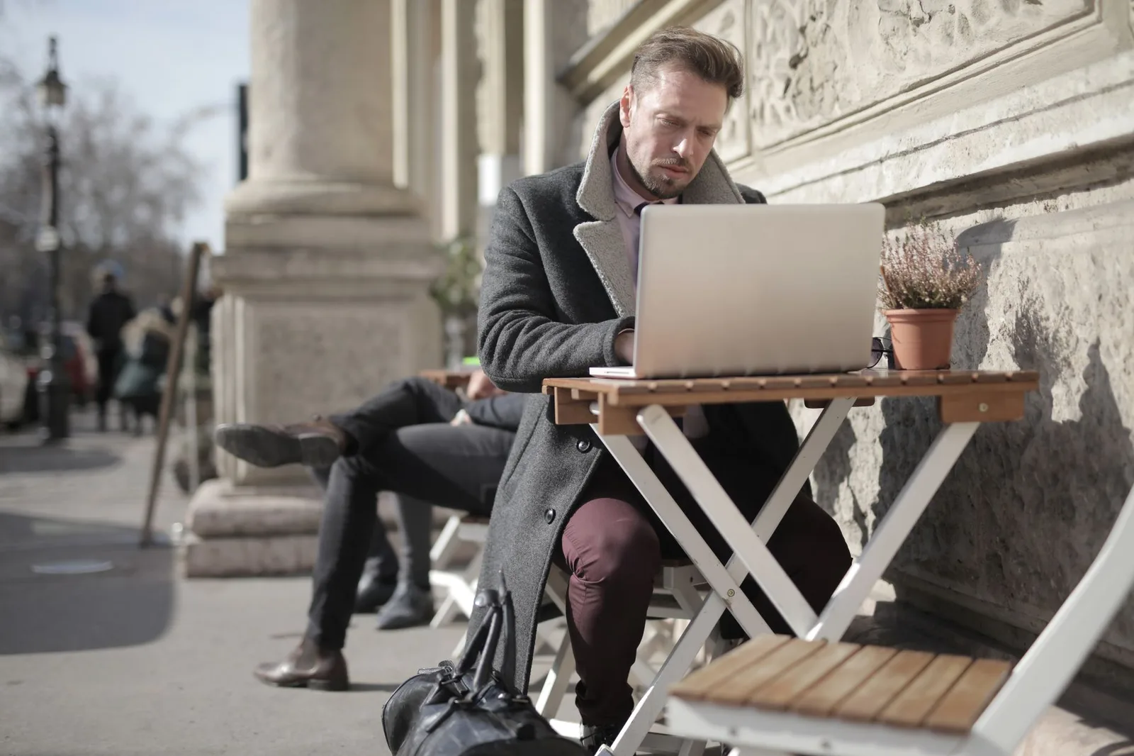 A remote worker with a laptop at an outdoor table in a city — the digital-nomad lifestyle, 2026