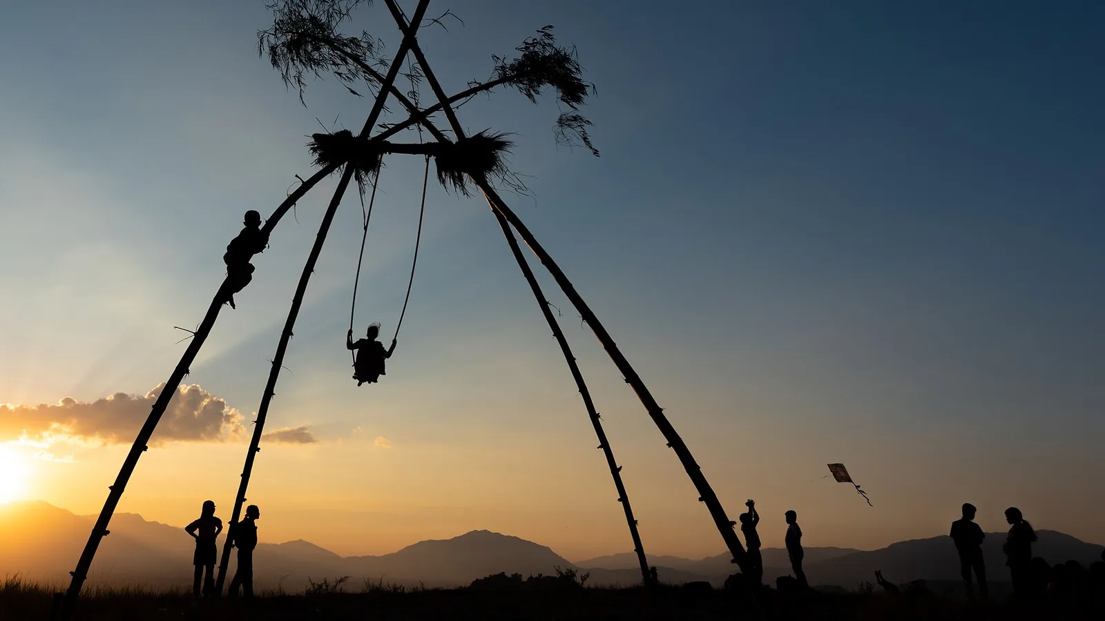 People flying kites and riding a traditional bamboo swing during the Dashain festival on the outskirts of the Kathmandu valley, Nepal