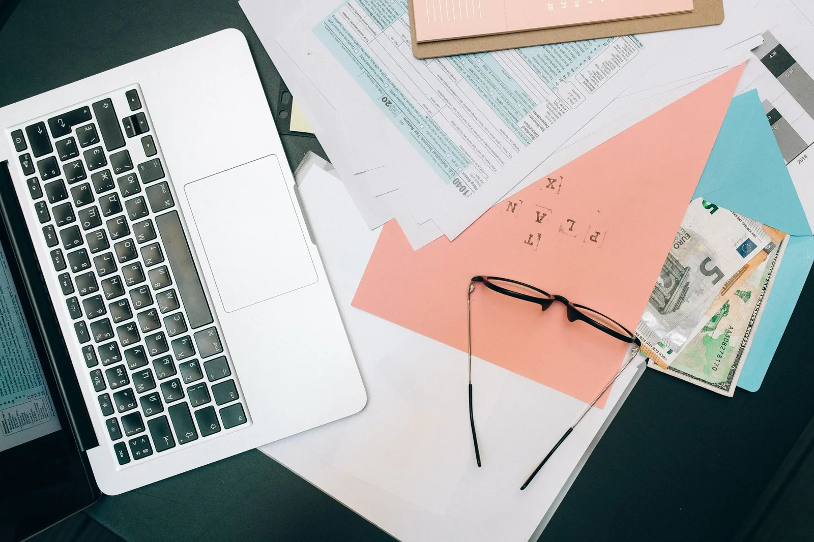 A laptop, a passport and tax paperwork with a calculator on a desk — working remotely abroad does not automatically make a digital nomad tax-free