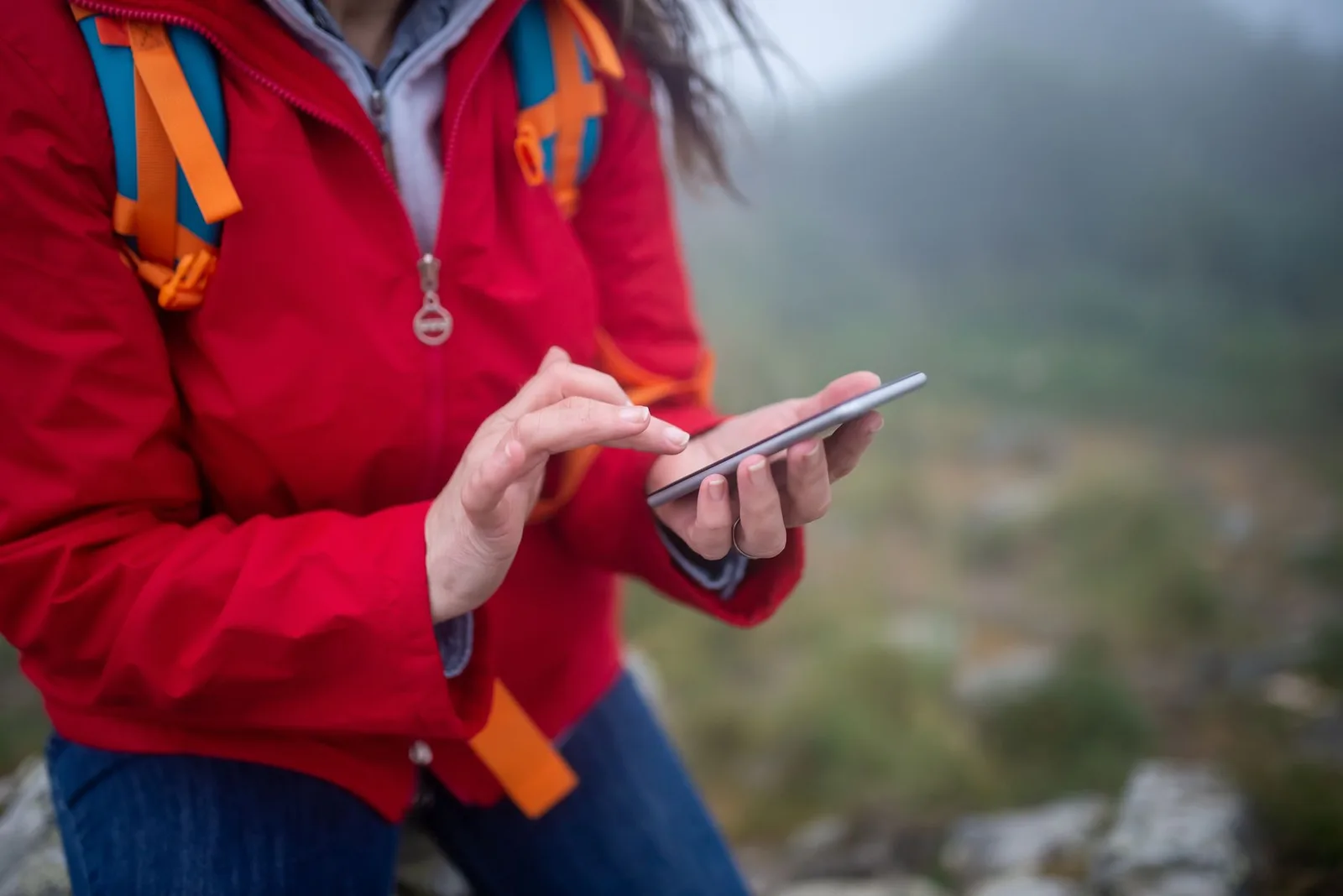 A hiker checking a smartphone on a mountain trail while trekking