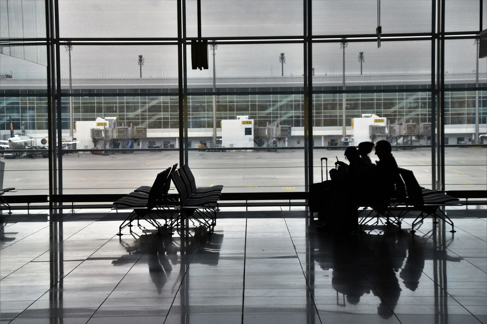 A family with young children and luggage walking through an airport terminal — illustrative of one family travel insurance policy covering parents and their children