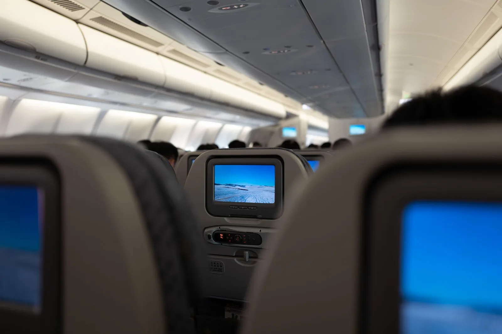 An empty lie-flat business-class cabin with wide reclining seats inside a wide-body passenger aircraft — the cabin most upgrade seekers are aiming for