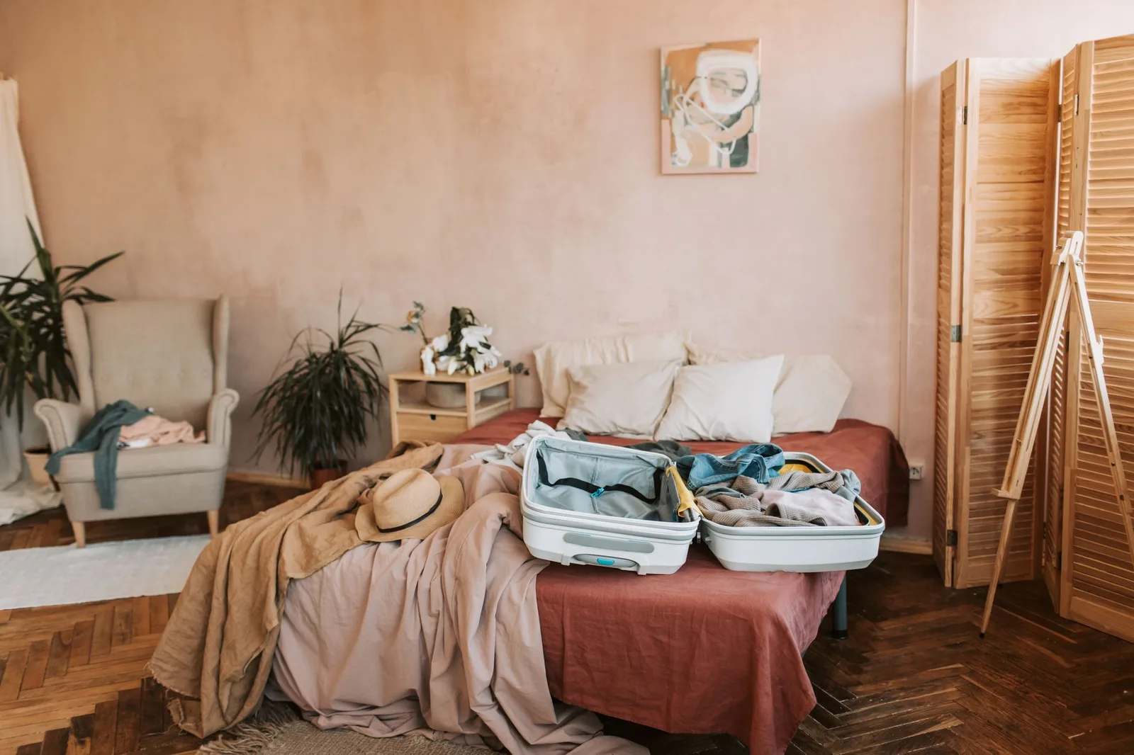 An open suitcase on a bed neatly packed with rolled clothes and packing cubes