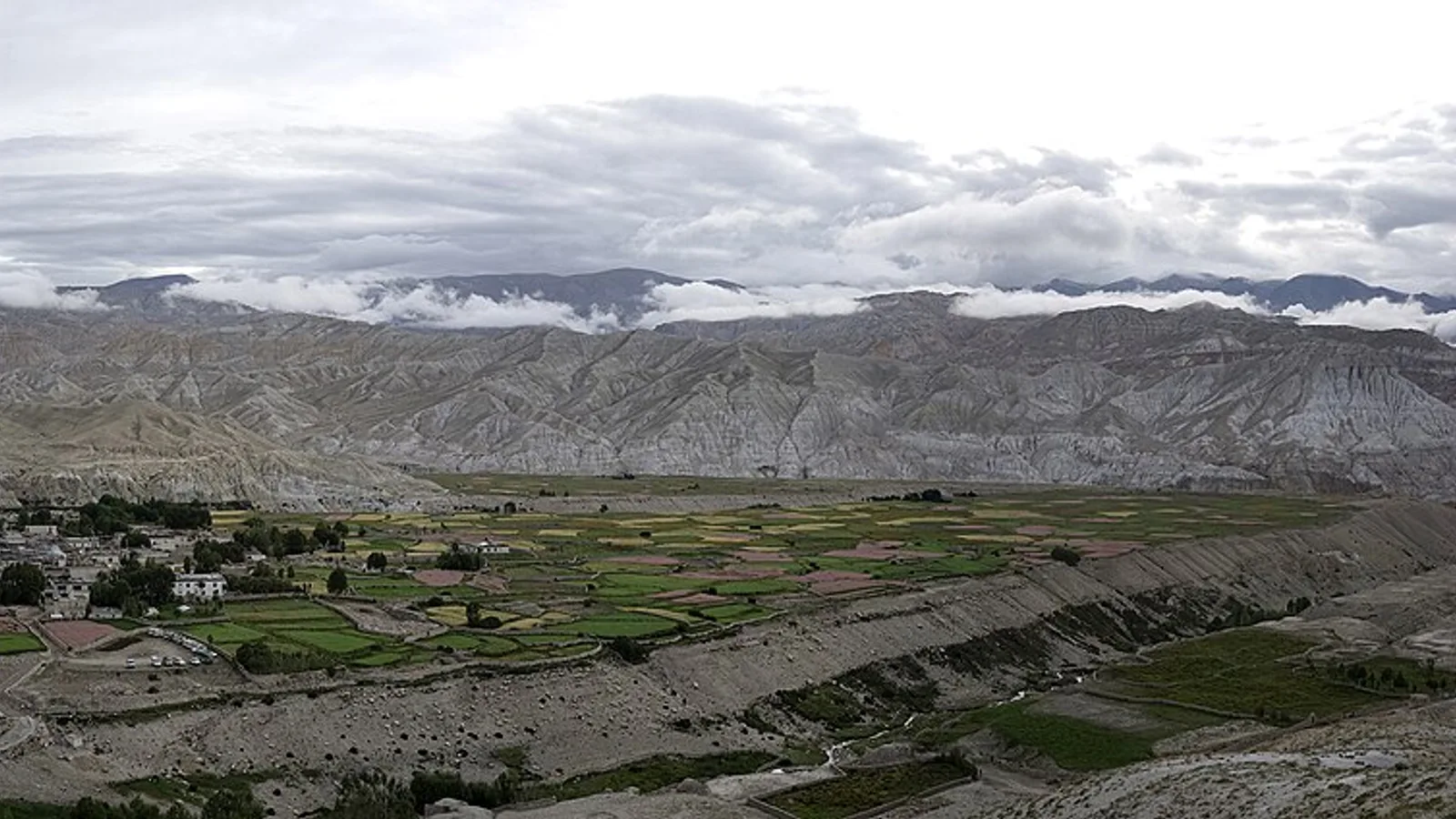 The eroded red cliffs and high desert of Upper Mustang around Lo Manthang in the rain shadow behind the Himalaya, Nepal — a dry high desert reached from Jomsom and unaffected by the 2026 Rasuwa flood