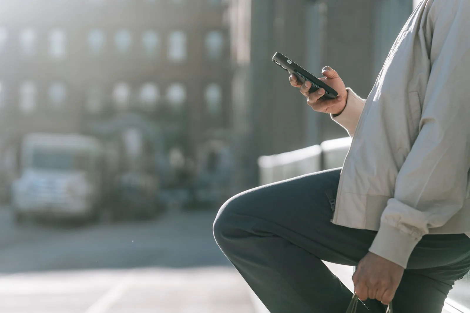 A traveller holding a smartphone on a city street abroad, checking the screen