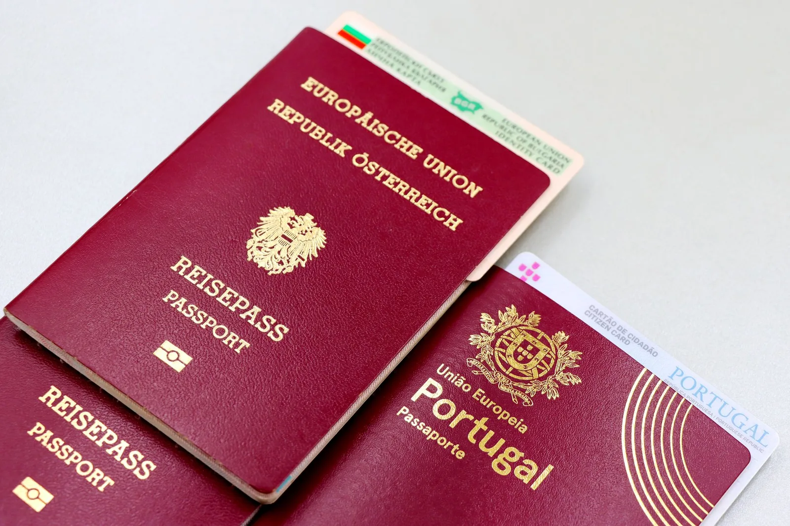 Burgundy European Union passports — an Austrian and a Portuguese passport alongside EU identity cards — laid on a table, the kind of travel documents ranked by the Henley Passport Index