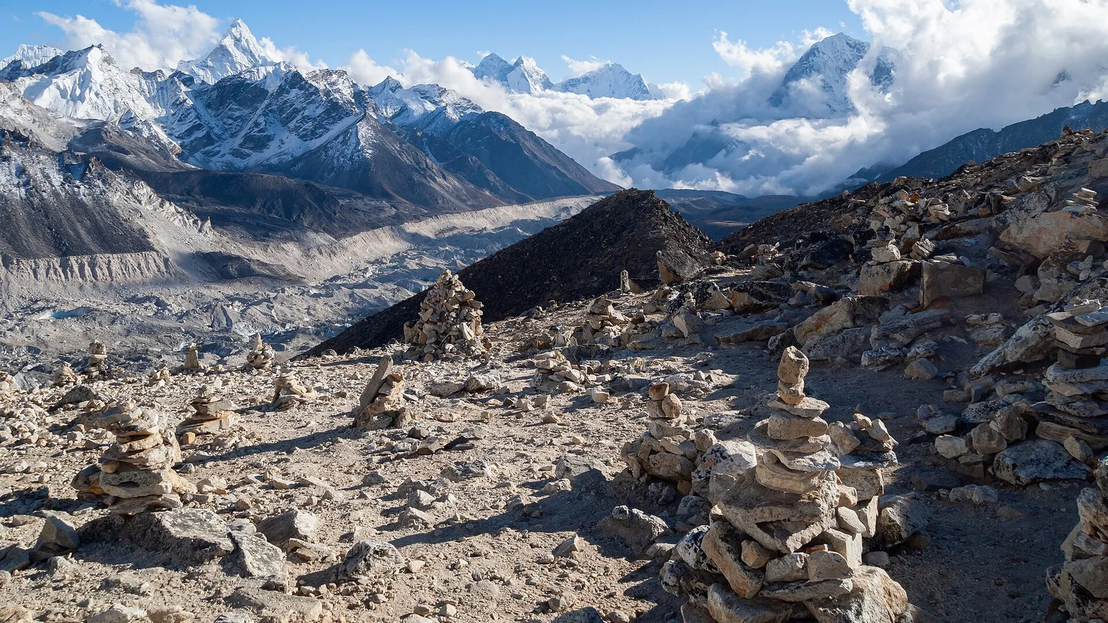 The rocky, debris-covered surface and moraine of a Himalayan glacier below snow-capped peaks in the Nepal Himalaya
