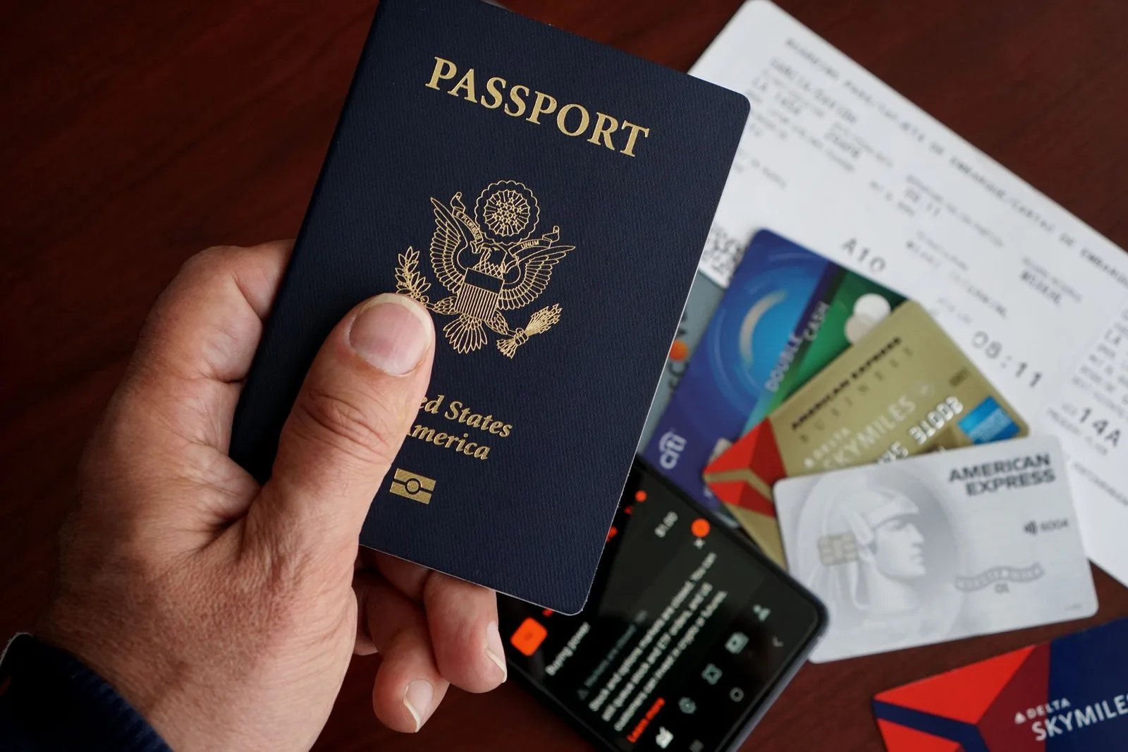 A passenger holding a passport and a boarding pass at an airline check-in desk — where proof of onward or return travel is checked before you fly