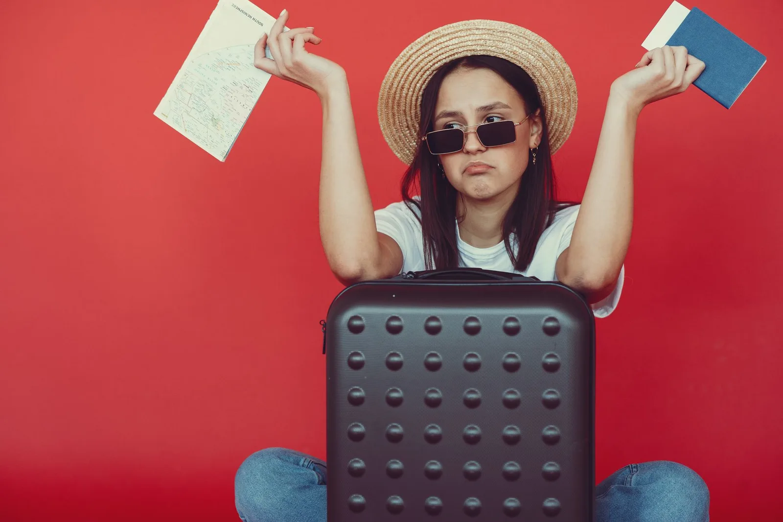An open suitcase packed for a holiday beside a folded map and a passport — planning a trip