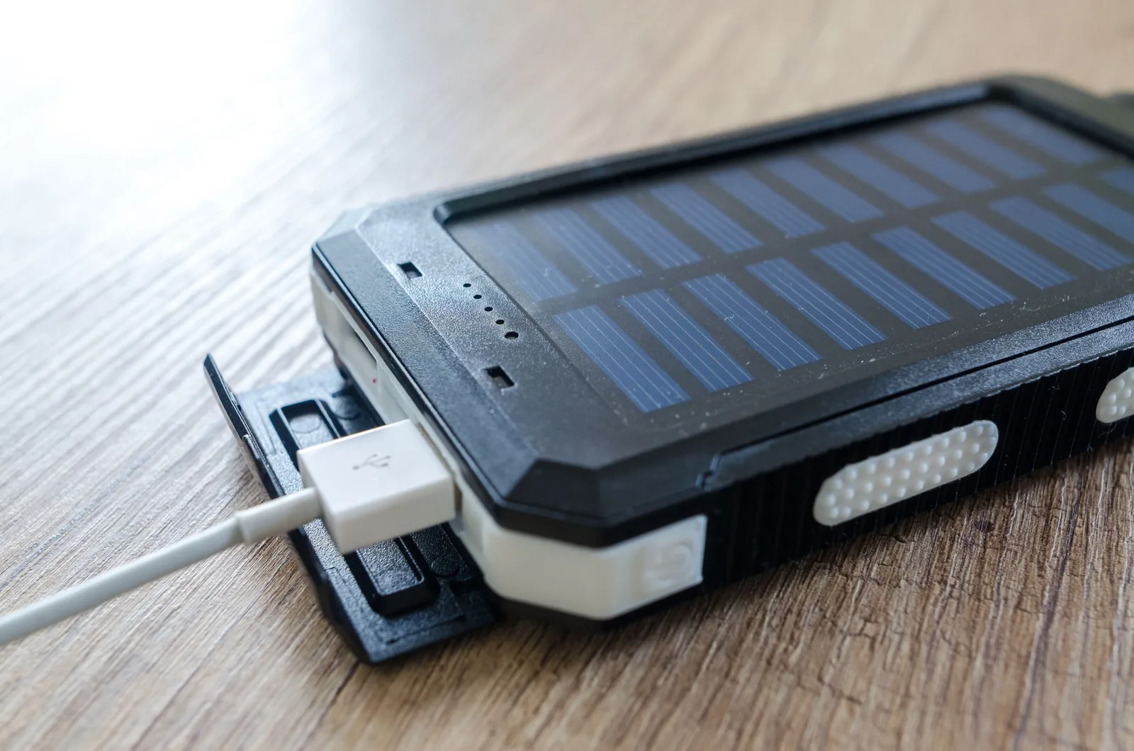 A portable power bank charging a smartphone with a USB cable beside travel items