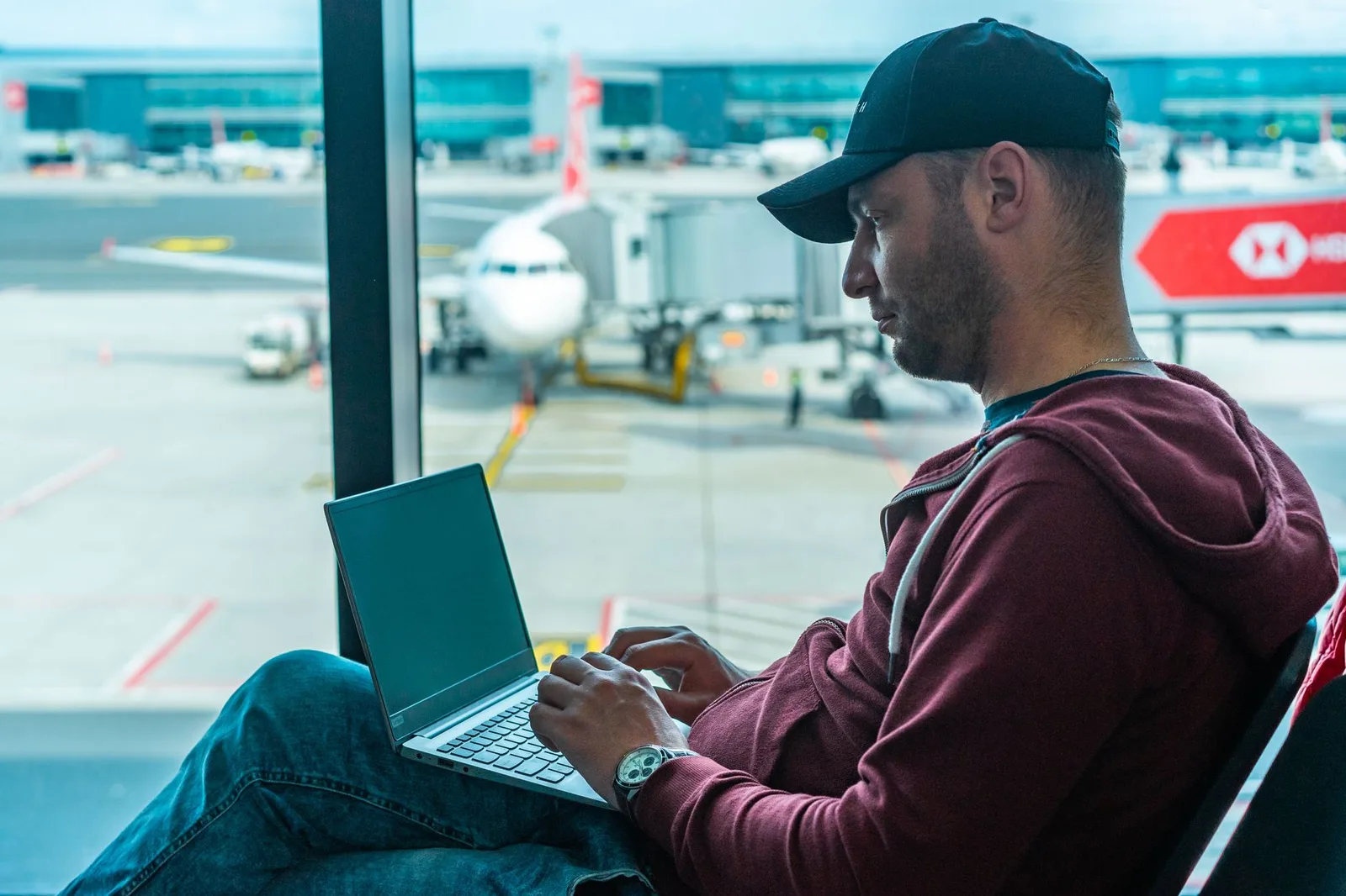 A traveller working on a laptop over public Wi-Fi at an airport cafe, with a phone beside the keyboard