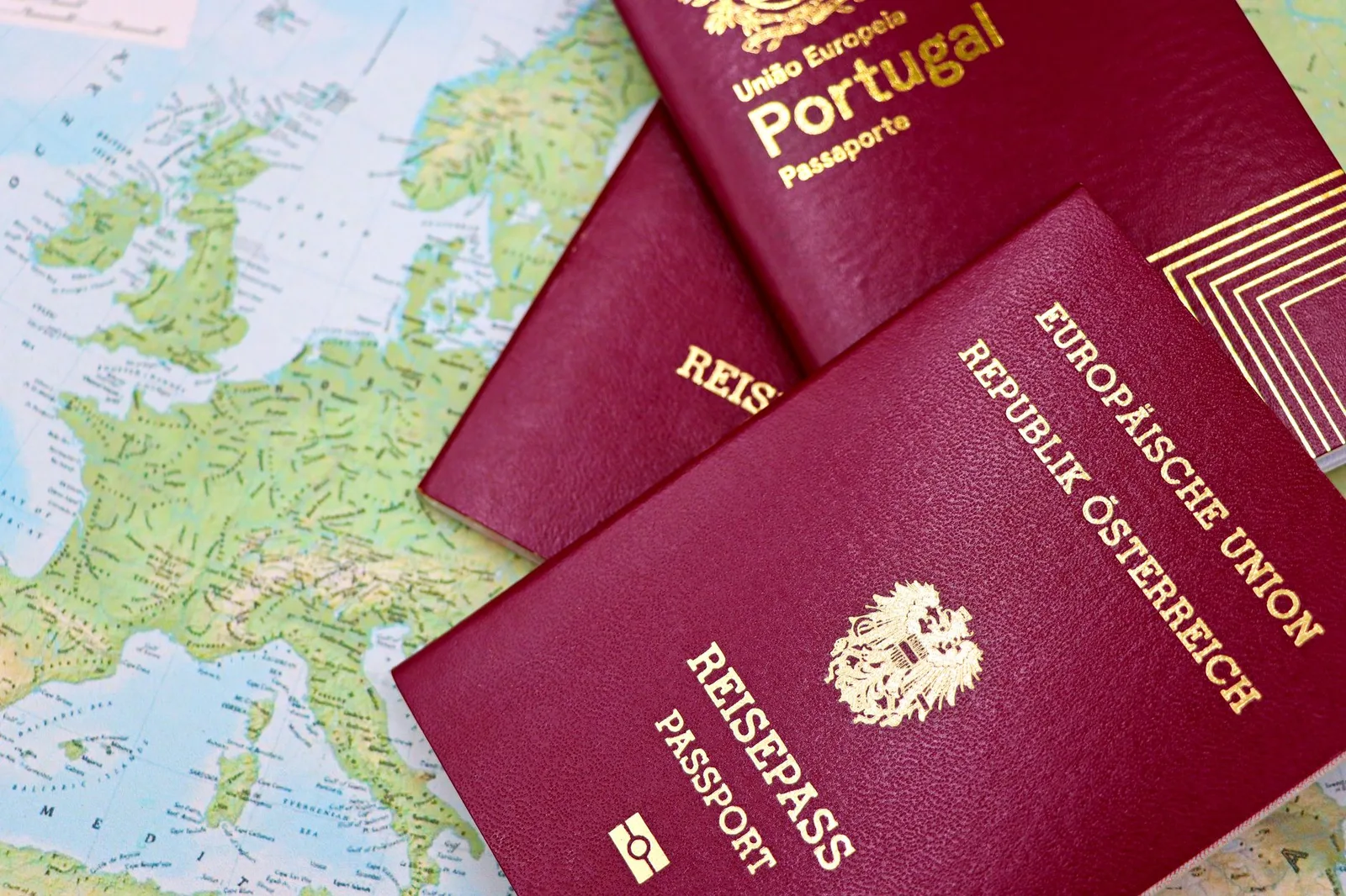 Several national passports fanned out on a desk with a boarding pass — illustrative of second citizenship and global mobility