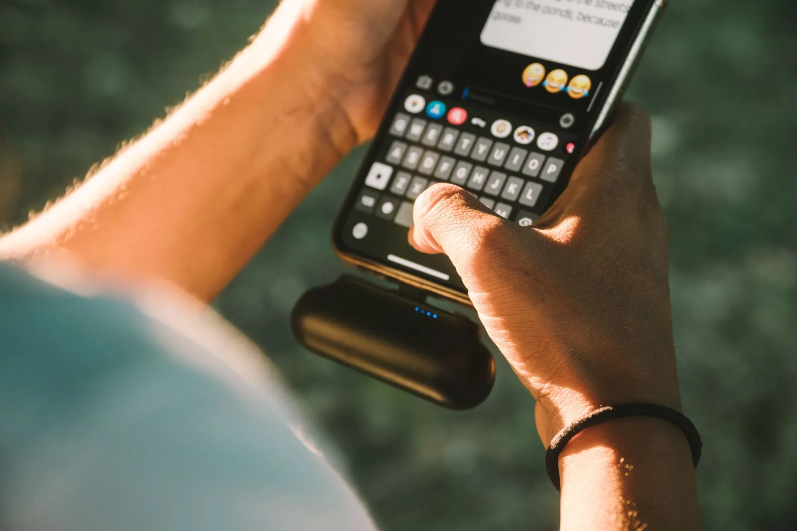 A compact portable power bank plugged into a smartphone to charge it outdoors