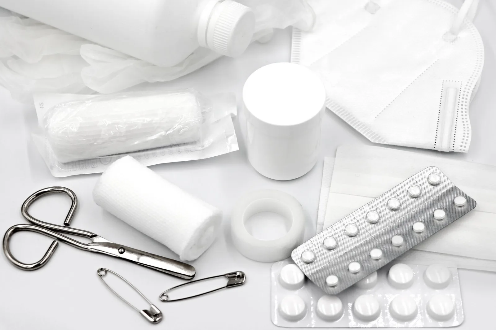 An open travel first-aid kit with plasters, bandages, medicines and tools laid out on a surface