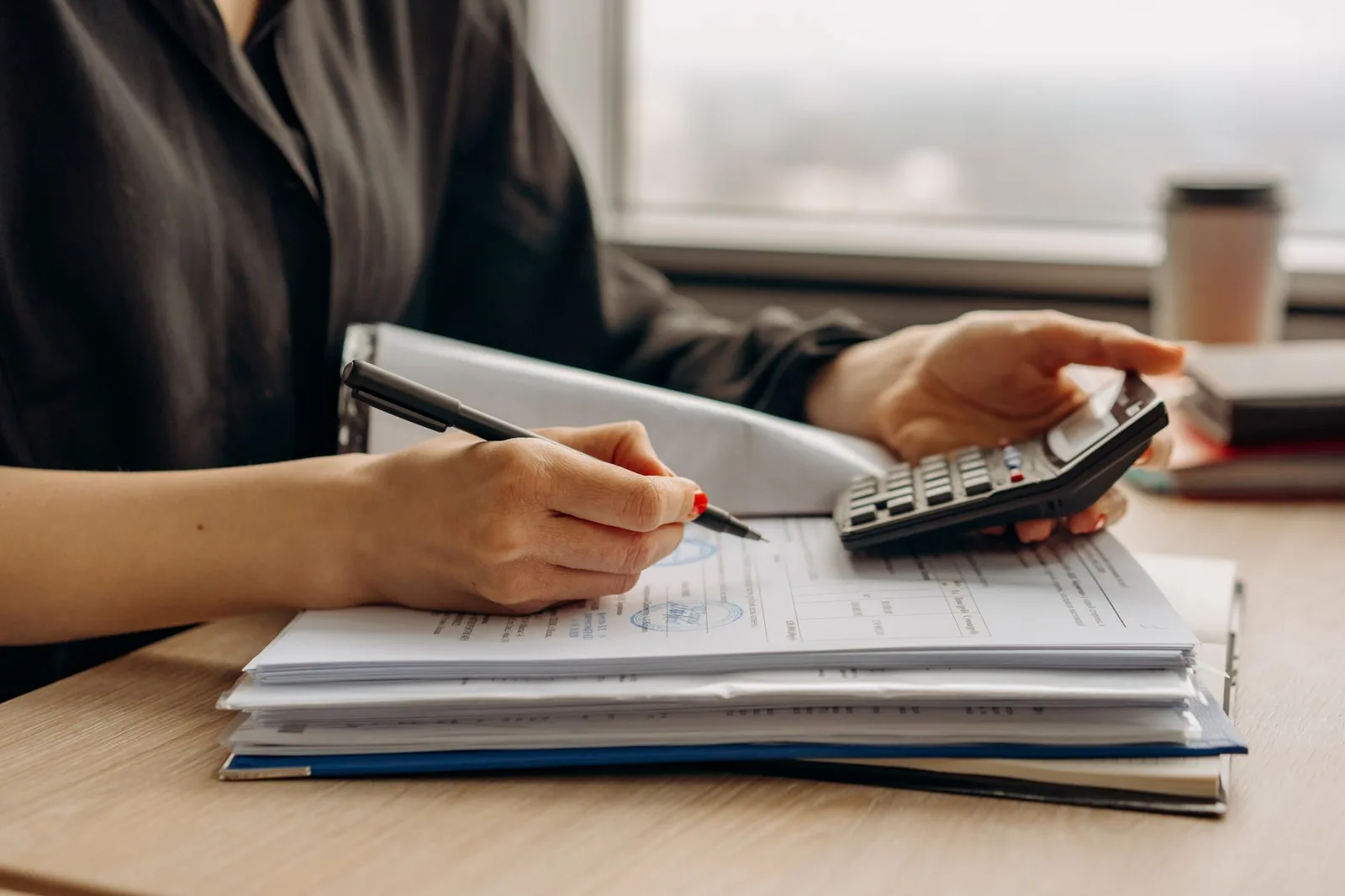 A person reviewing an insurance policy document at a desk with a calculator and pen, working out the excess before signing