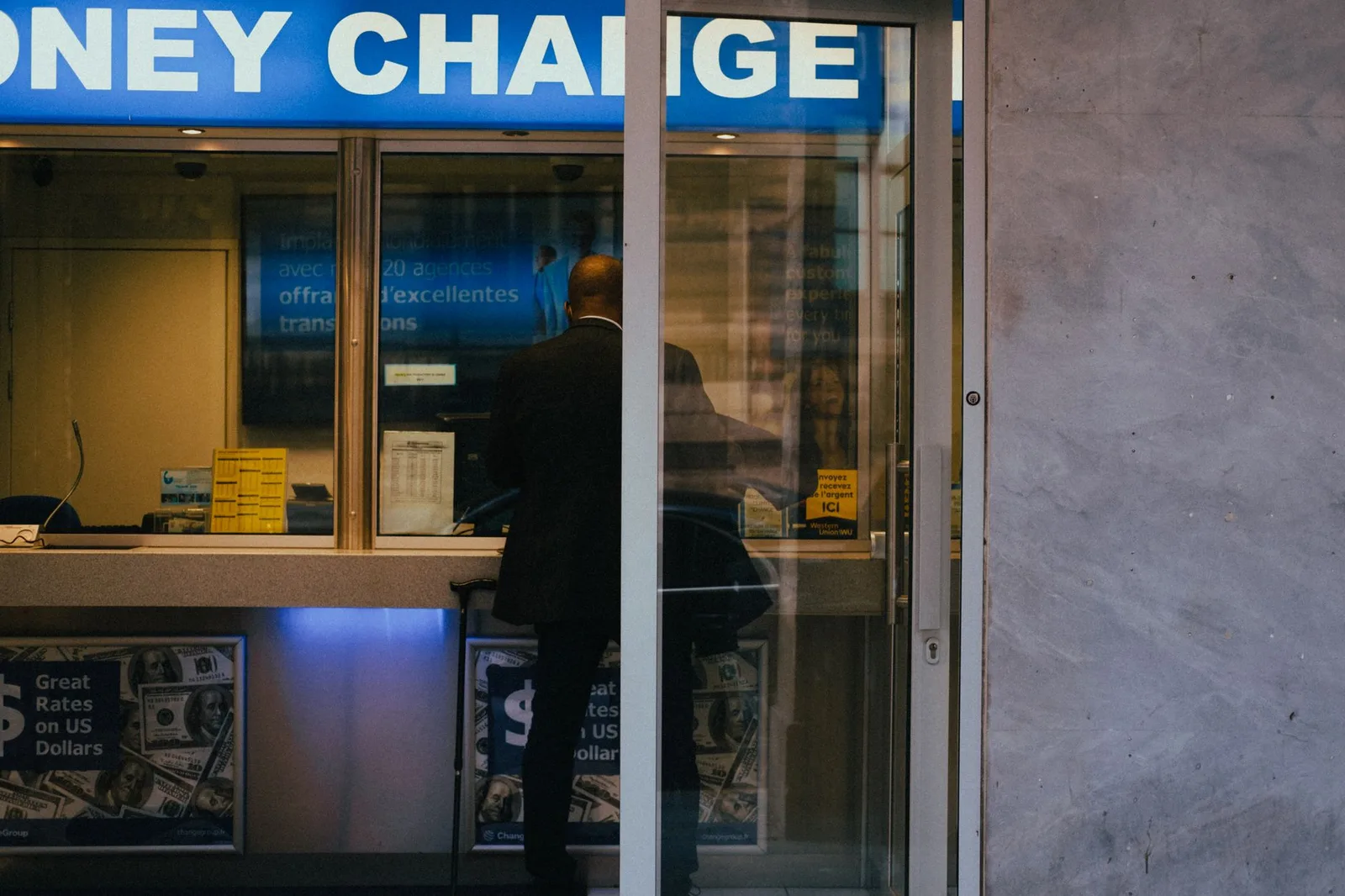A currency exchange bureau counter with a foreign-exchange rates board and bundles of banknotes in different currencies