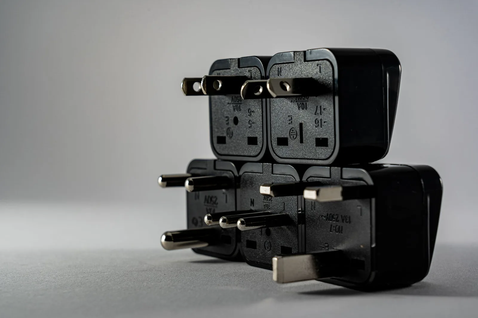 A universal travel plug adapter with multiple international plug pins and USB ports beside a wall socket
