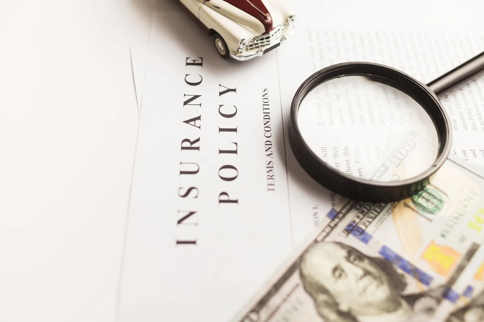 The dense small print of an insurance policy document under a magnifying glass, where the exclusions that void a claim are written