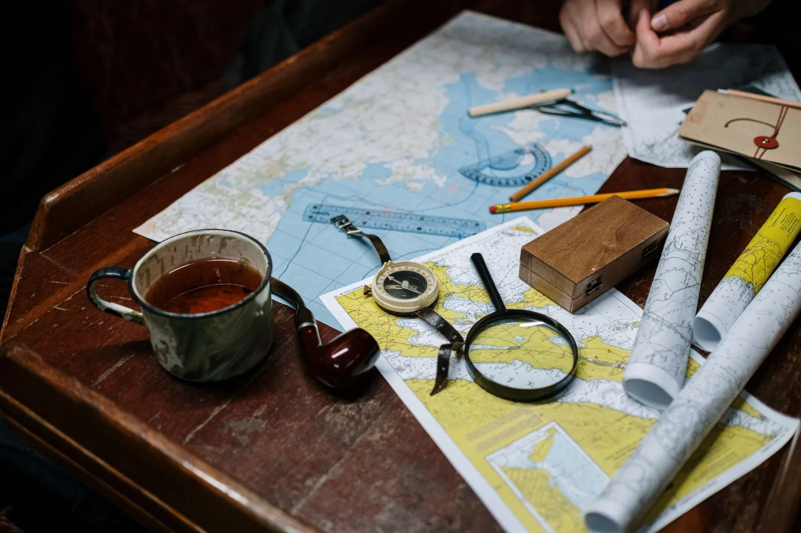 A world map spread on a desk with a compass, coloured pins and a small globe — planning where to travel month by month across the year