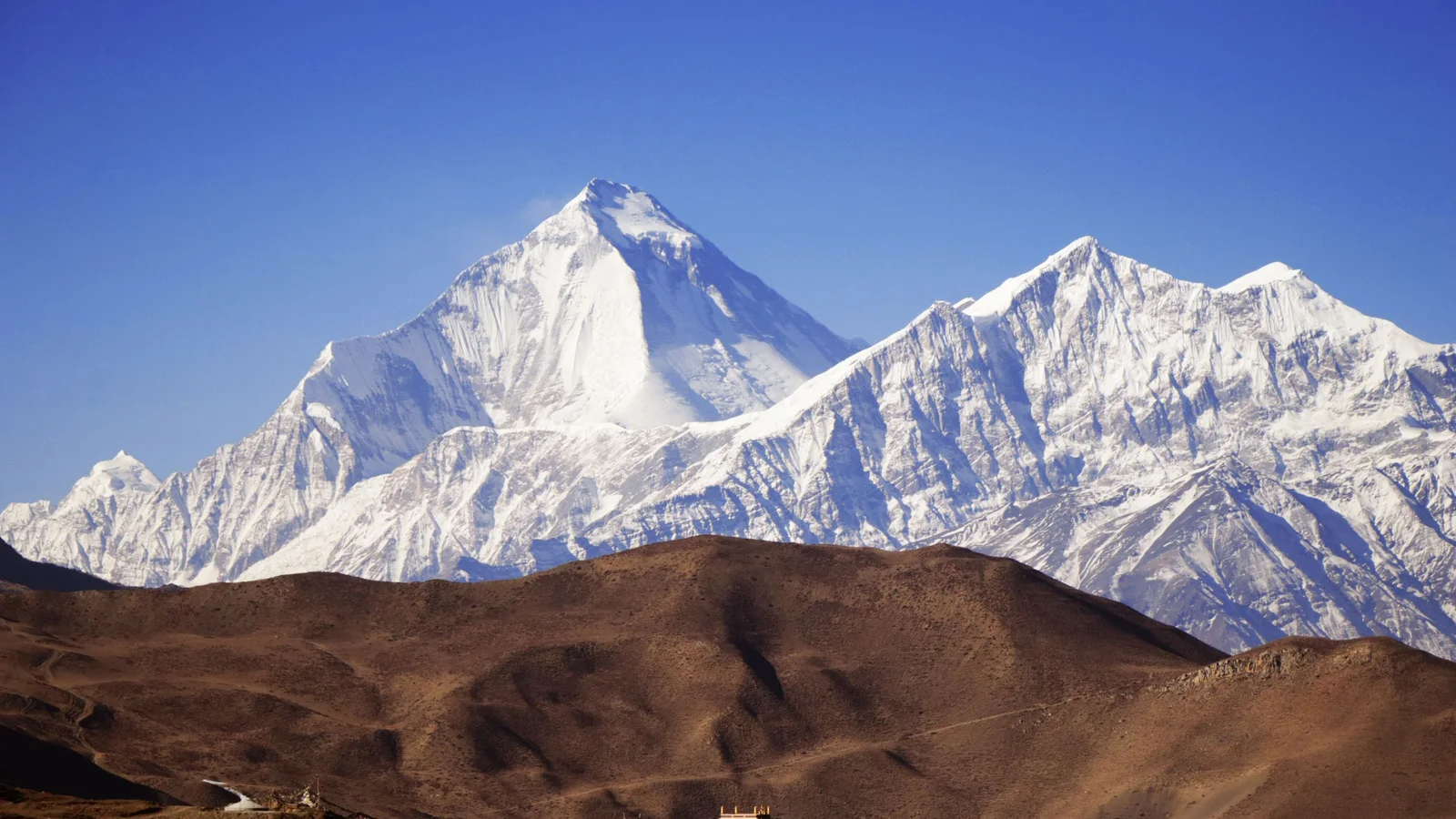 Majestic snow-capped peaks of the Himalayas under a clear blue sky, offering a stunning landscape view.