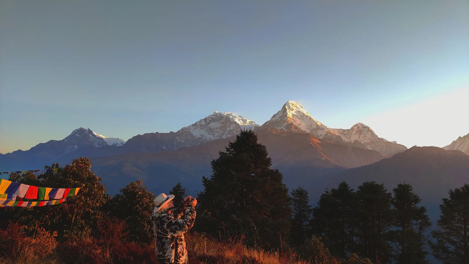 A person taking a photo of the Annapurna mountain range at sunrise in Ghode Pani, Nepal.