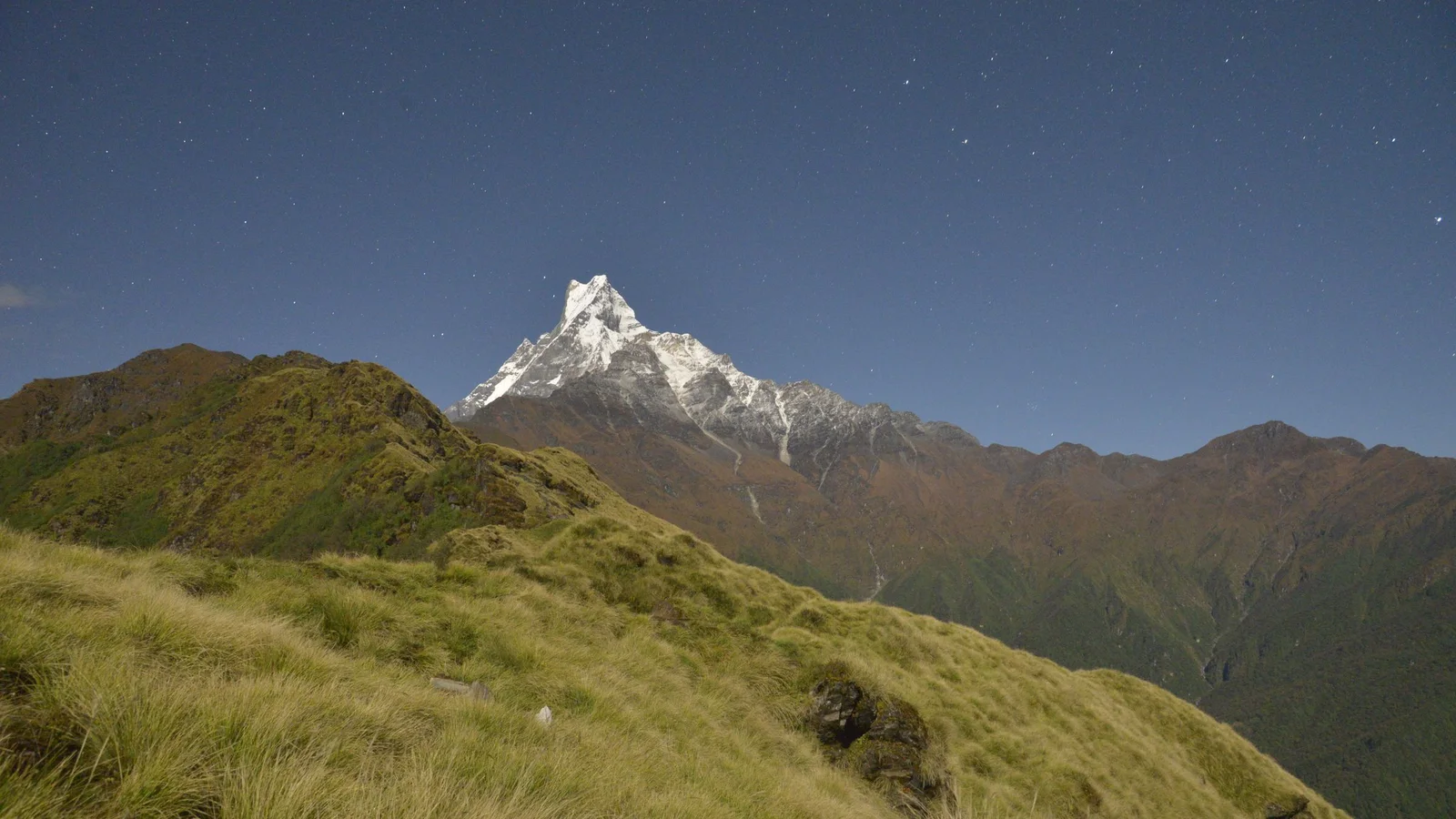 Breathtaking view of snow-capped mountains under a starry night sky, showcasing serene nature.