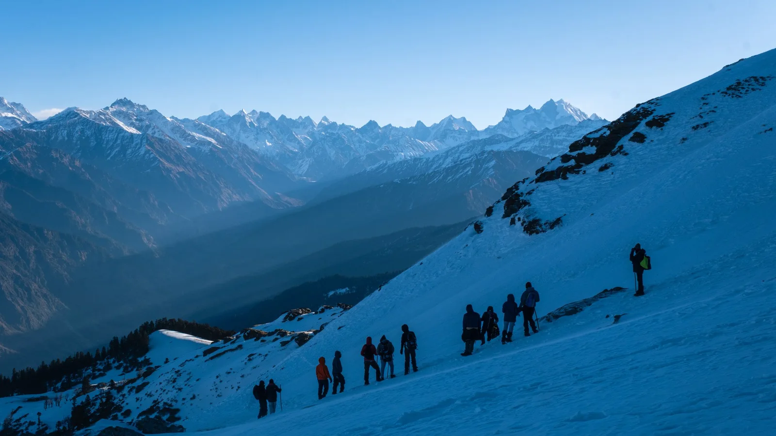 Group of trekkers navigating snowy slopes in the majestic Singtur Range, India.