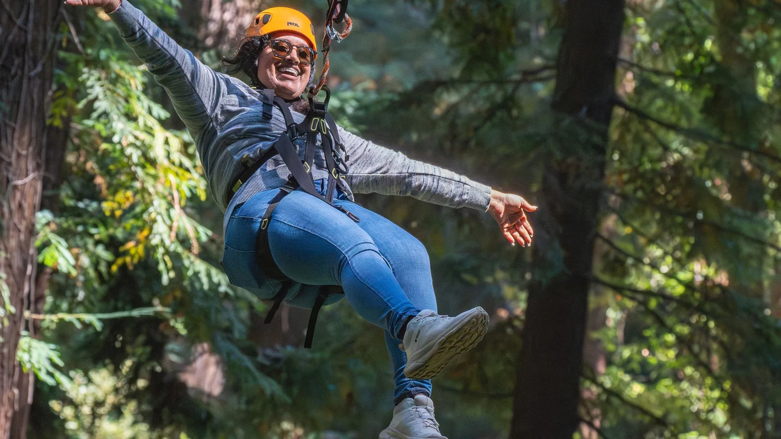 Woman ziplining through a lush forest, embracing adventure and enjoying the thrill of nature.